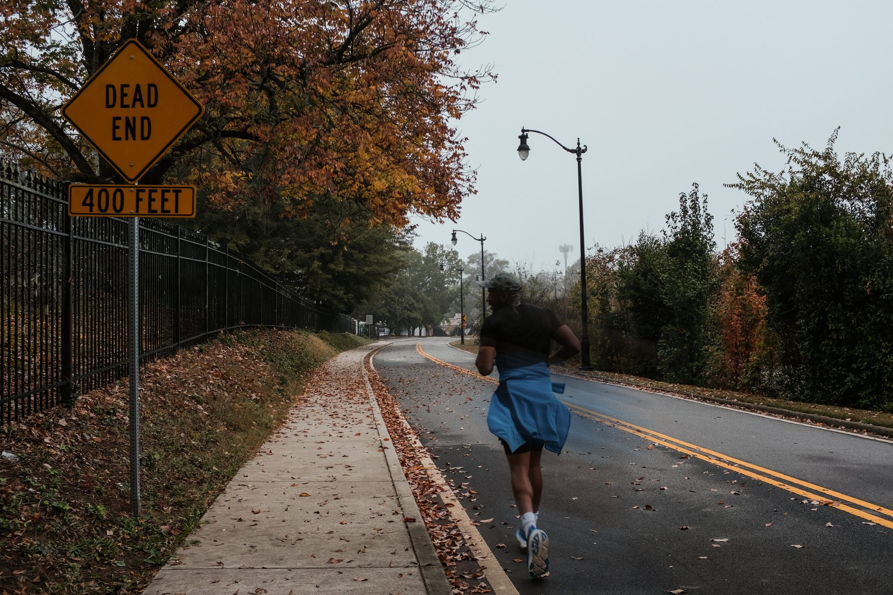 A runner heading past a dead end sign on a foggy morning